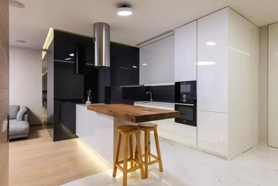 Cozinha integrada à sala com armários brancos de alto brilho e ilha com banquetas